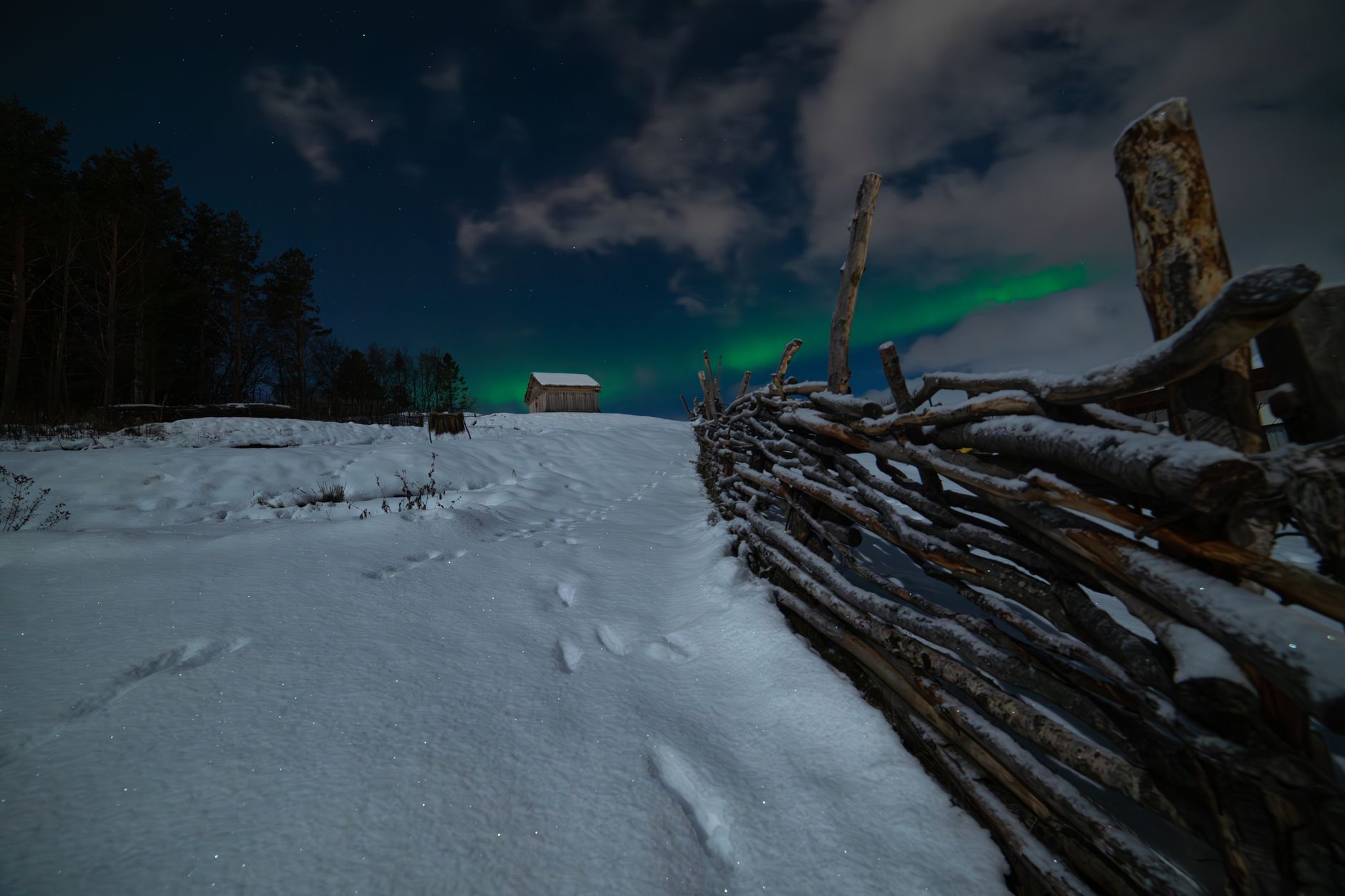 A timber sauna on the edge of icy water under Arctic dusk